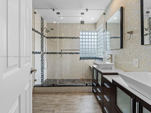 171 NW 152nd Ave, Pembroke Pines, FL 33028 - bathroom with tile walls, a stall shower, double vanity, wood finished floors, and tasteful backsplash