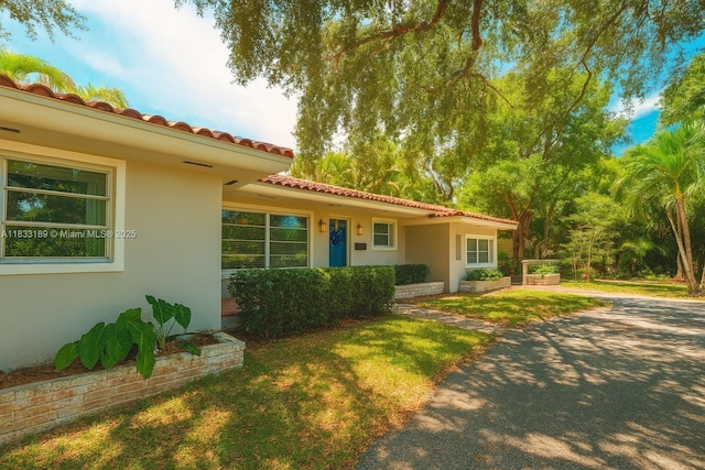 1180 NE 102nd St, Miami Shores, FL 33138 - mediterranean / spanish-style home with stucco siding, a tiled roof, and a front lawn