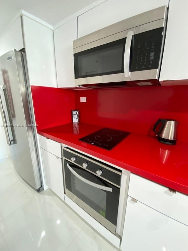 19201 Collins Ave Unit 130, Sunny Isles Beach, FL 33160 - kitchen featuring stainless steel appliances, white cabinetry, and light marble finish flooring