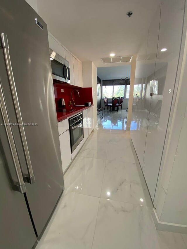 19201 Collins Ave Unit 130, Sunny Isles Beach, FL 33160 - kitchen with stainless steel appliances, modern cabinets, white cabinets, and light marble finish flooring