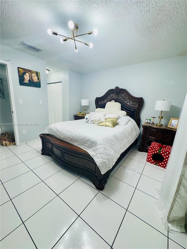 5072 W 12th Ln Unit D-14, Hialeah, FL 33012 - bedroom featuring a closet, a textured ceiling, a chandelier, and light tile patterned floors
