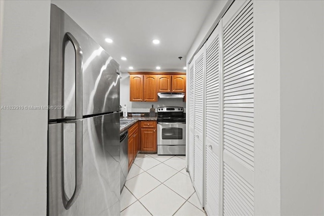 540 Brickell Key Dr Unit 412, Miami, FL 33131 - kitchen with stainless steel appliances, under cabinet range hood, recessed lighting, light tile patterned floors, and brown cabinetry