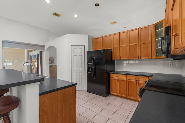 2373 NW 195th Ave, Pembroke Pines, FL 33029 - kitchen with black appliances, dark countertops, arched walkways, light tile patterned floors, and brown cabinetry