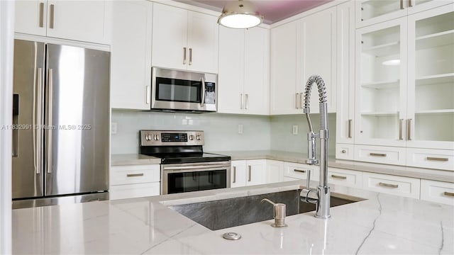 1491 SE 25th Ter Unit 1491, Homestead, FL 33035 - kitchen featuring stainless steel appliances, white cabinets, light stone countertops, and glass insert cabinets