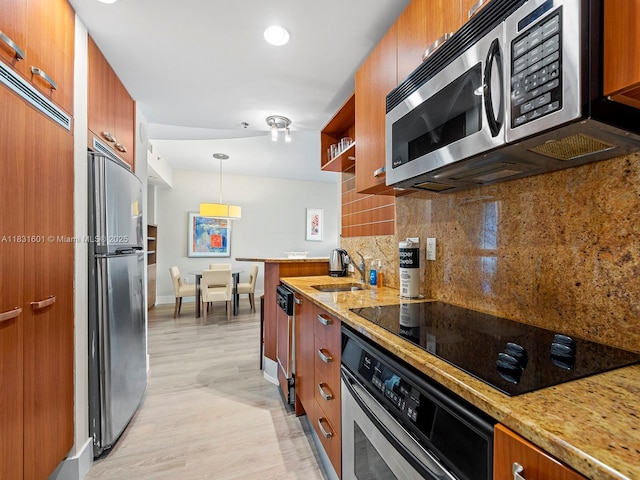 1395 Brickell Ave Unit 3310, Miami, FL 33131 - kitchen featuring appliances with stainless steel finishes, brown cabinets, light wood-style flooring, decorative backsplash, and light stone counters