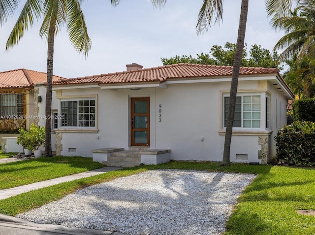 9033 Carlyle Ave, Surfside, FL 33154 - mediterranean / spanish-style house featuring stucco siding, a front yard, a tile roof, and a chimney