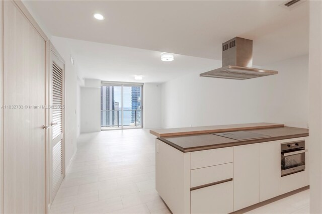 1000 Brickell Plz Unit 3703, Miami, FL 33131 - kitchen featuring range hood, oven, electric cooktop, white cabinets, and open floor plan