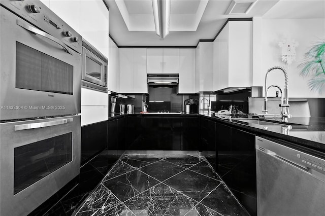 1425 Brickell Ave Unit 42E, Miami, FL 33131 - kitchen with stainless steel appliances, modern cabinets, dark countertops, dark marble finish floors, and white cabinetry