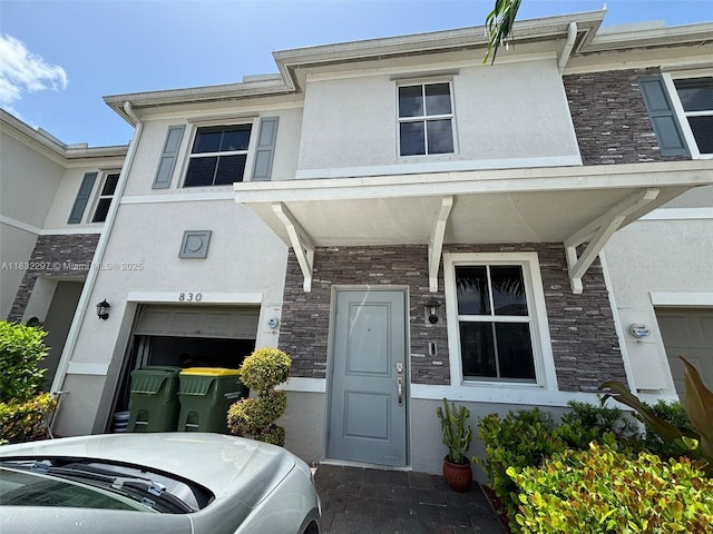 830 SE 19th St, Homestead, FL 33034 - view of property featuring stucco siding, stone siding, and an attached garage