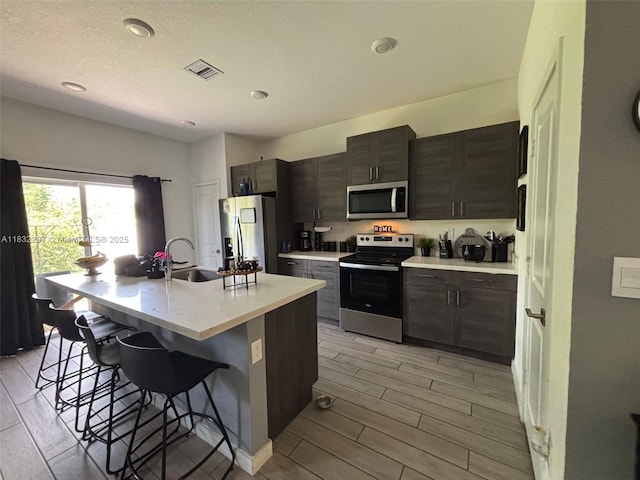 830 SE 19th St, Homestead, FL 33034 - kitchen featuring stainless steel appliances, a kitchen bar, light countertops, an island with sink, and wood tiled floors