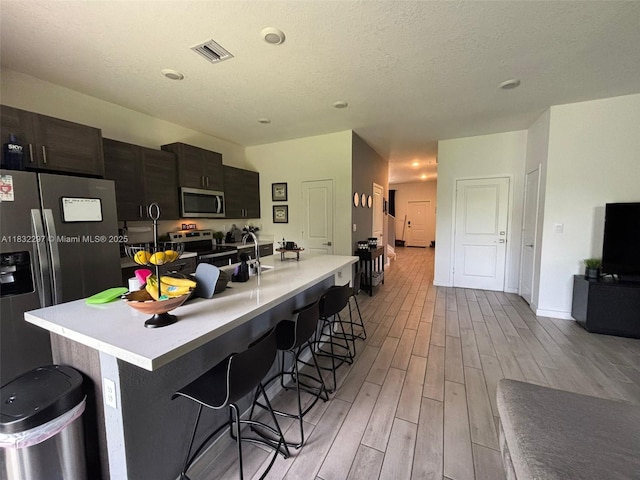 830 SE 19th St, Homestead, FL 33034 - kitchen with appliances with stainless steel finishes, light wood-type flooring, a kitchen breakfast bar, a center island with sink, and light countertops
