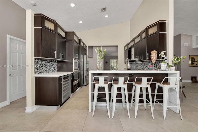14460 Glencairn Rd, Miami Lakes, FL 33016 - kitchen with wine cooler, stainless steel appliances, decorative backsplash, a kitchen bar, and recessed lighting