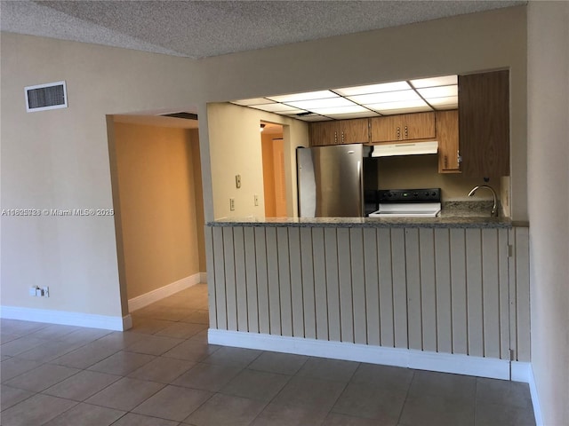 5995 Washington St Unit 233, Hollywood, FL 33023 - kitchen with freestanding refrigerator, under cabinet range hood, range, brown cabinetry, and tile patterned floors
