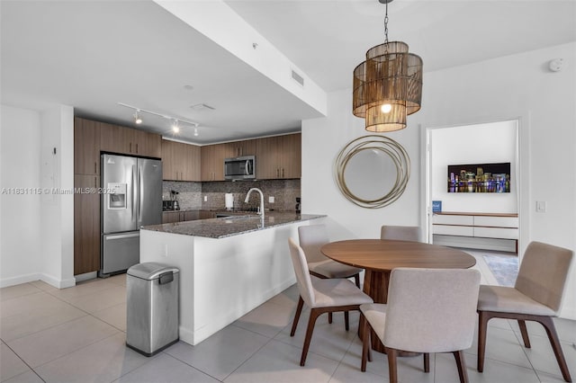 5350 NW 84th Ave Unit 1513, Doral, FL 33166 - kitchen featuring appliances with stainless steel finishes, a peninsula, decorative backsplash, dark stone countertops, and rail lighting