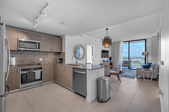 5350 NW 84th Ave Unit 1513, Doral, FL 33166 - kitchen featuring appliances with stainless steel finishes, a peninsula, decorative backsplash, stone countertops, and open floor plan