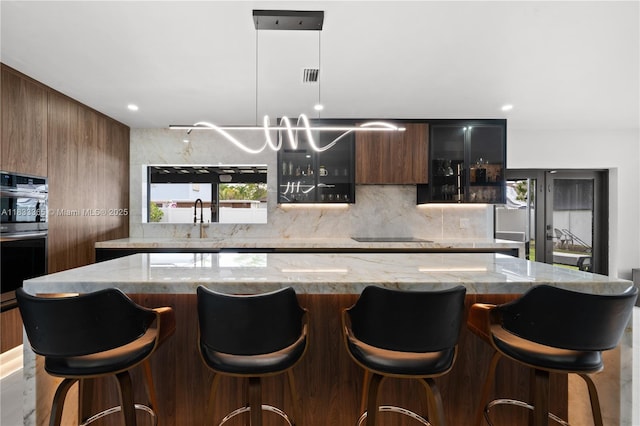 18082 SW 152nd Ct, Miami, FL 33187 - kitchen with modern cabinets, backsplash, double oven, glass insert cabinets, and light stone countertops
