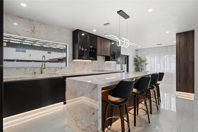 18082 SW 152nd Ct, Miami, FL 33187 - kitchen featuring modern cabinets, backsplash, a breakfast bar area, light stone countertops, and decorative light fixtures