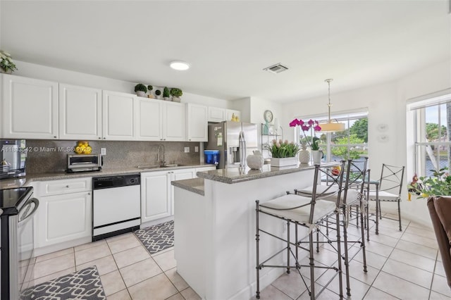 9364 SW 164th Ct, Miami, FL 33196 - kitchen with appliances with stainless steel finishes, light tile patterned floors, backsplash, white cabinetry, and a breakfast bar