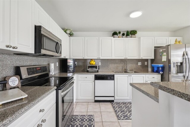9364 SW 164th Ct, Miami, FL 33196 - kitchen with appliances with stainless steel finishes, white cabinets, tasteful backsplash, light tile patterned floors, and dark stone counters