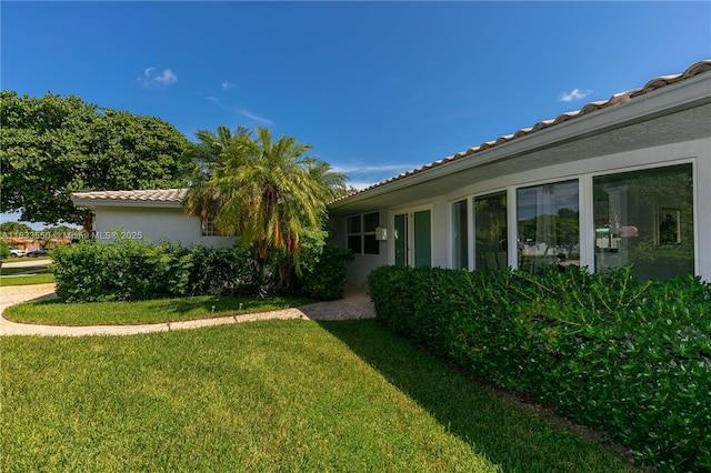 4326 Jackson St, Hollywood, FL 33021 - view of side of property featuring a lawn, a tile roof, and stucco siding