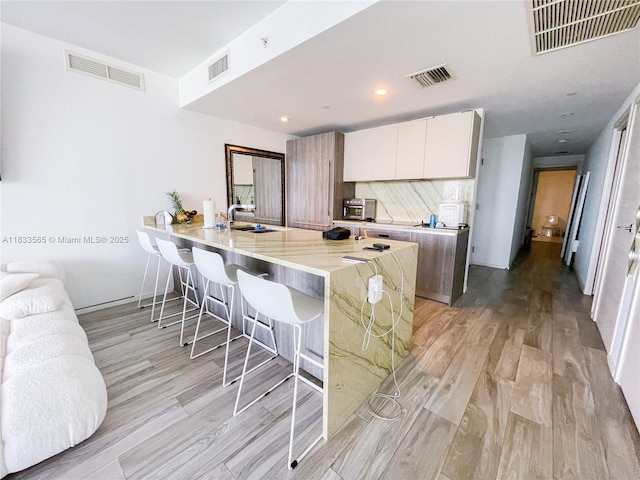 801 S Miami Ave Unit 4204, Miami, FL 33130 - kitchen featuring a breakfast bar area, light wood-type flooring, white cabinets, and a peninsula