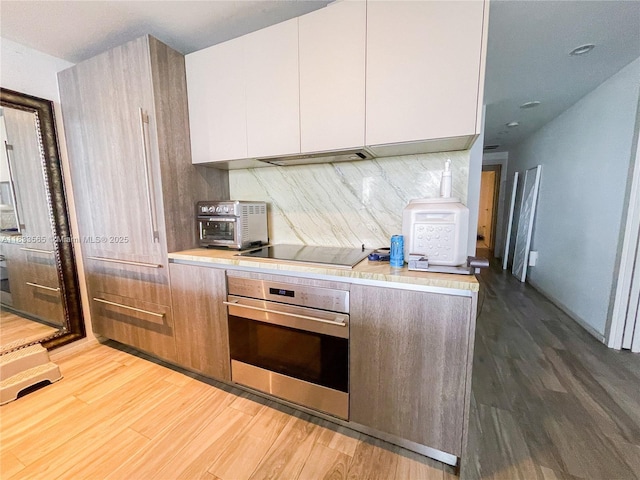 801 S Miami Ave Unit 4204, Miami, FL 33130 - kitchen with stainless steel oven, wood finished floors, light countertops, decorative backsplash, and white cabinetry