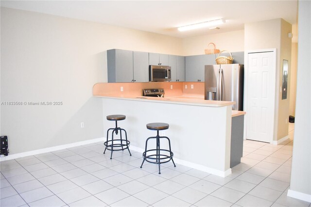 9123 SW 152nd Path, Miami, FL 33196 - kitchen featuring appliances with stainless steel finishes, a breakfast bar area, gray cabinetry, a peninsula, and light countertops