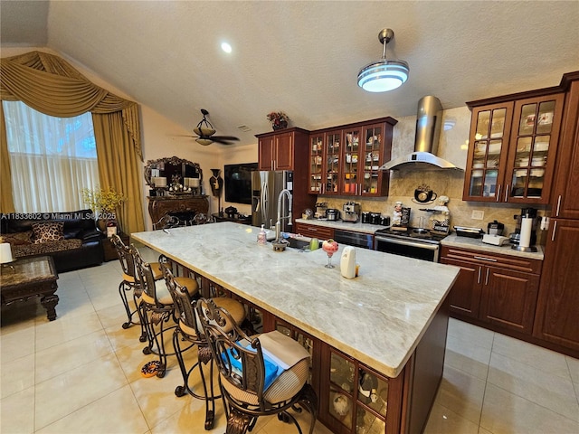 15126 NW 90th Ct, Miami Lakes, FL 33018 - kitchen featuring appliances with stainless steel finishes, wall chimney exhaust hood, light tile patterned floors, open floor plan, and a kitchen bar