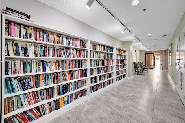 2541 N Nob Hill Rd Unit 309, Sunrise, FL 33322 - sitting room featuring wall of books, track lighting, a textured ceiling, and tile patterned floors