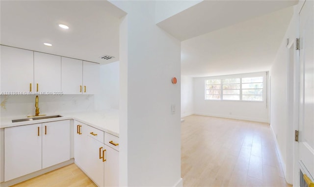 1333 E Hallandale Beach Blvd Unit 326, Hallandale Beach, FL 33009 - kitchen featuring light countertops, white cabinetry, recessed lighting, light wood finished floors, and tasteful backsplash