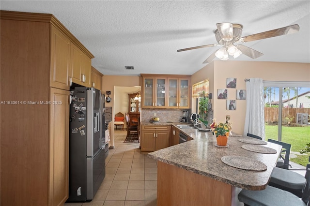 15824 Cotswold Ct, Davie, FL 33331 - kitchen featuring appliances with stainless steel finishes, a peninsula, a kitchen bar, light tile patterned flooring, and glass insert cabinets