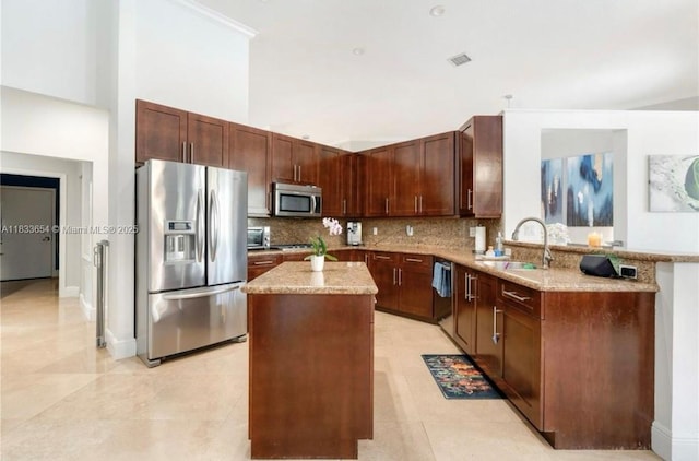 14095 NW 22nd Ct, Pembroke Pines, FL 33028 - kitchen featuring appliances with stainless steel finishes, light stone counters, a center island, decorative backsplash, and a peninsula
