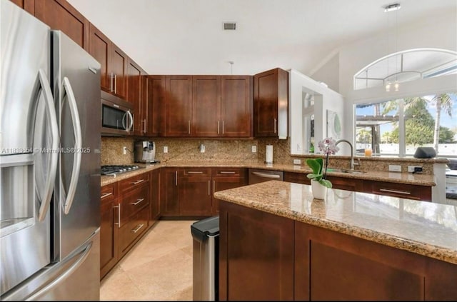 14095 NW 22nd Ct, Pembroke Pines, FL 33028 - kitchen with appliances with stainless steel finishes, backsplash, decorative light fixtures, light stone countertops, and light tile patterned flooring