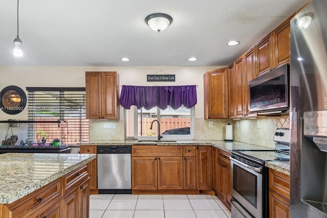 8107 NW 73rd Ter, Tamarac, FL 33321 - kitchen featuring stainless steel appliances, brown cabinets, healthy amount of natural light, light stone countertops, and recessed lighting