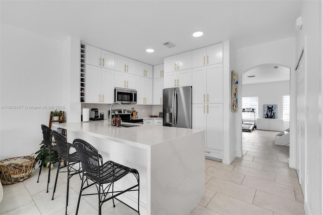 8242 NW 107th Ct Unit 7-12, Doral, FL 33178 - kitchen featuring appliances with stainless steel finishes, arched walkways, a peninsula, light countertops, and a kitchen breakfast bar
