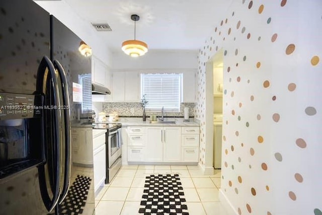 6443 Perry St, Hollywood, FL 33024 - kitchen featuring black refrigerator with ice dispenser, stainless steel electric range, light countertops, white cabinetry, and wallpapered walls