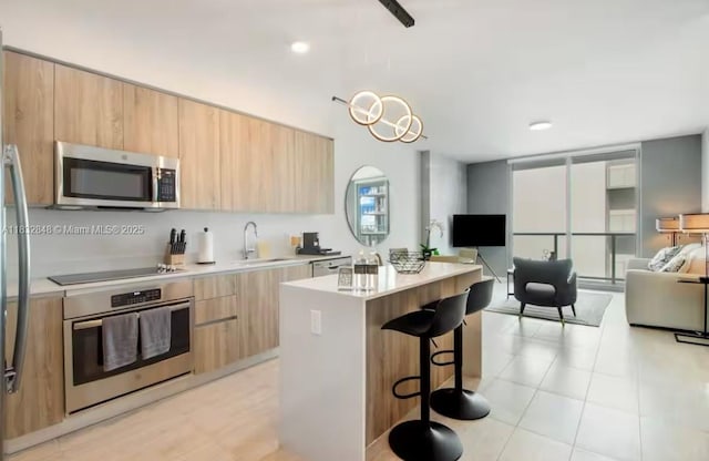 3900 Biscayne Blvd Unit S-1020, Miami, FL 33137 - kitchen with appliances with stainless steel finishes, modern cabinets, light brown cabinets, a kitchen breakfast bar, and a kitchen island