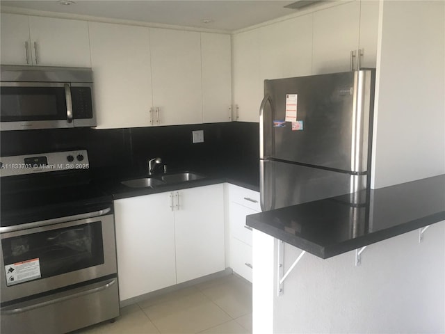 1750 NE 115th St Unit 608, Miami, FL 33181 - kitchen featuring appliances with stainless steel finishes, dark countertops, white cabinetry, and light tile patterned floors