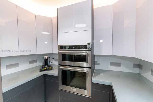 8694 Via Reale Unit 61L, Boca Raton, FL 33496 - kitchen with double oven, modern cabinets, tasteful backsplash, and light countertops