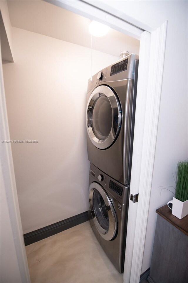 8694 Via Reale Unit 61L, Boca Raton, FL 33496 - laundry area featuring stacked washer / dryer and baseboards