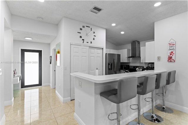5400 NW 184th St, Miami Gardens, FL 33055 - kitchen featuring stainless steel appliances, wall chimney range hood, a kitchen bar, a peninsula, and a textured ceiling