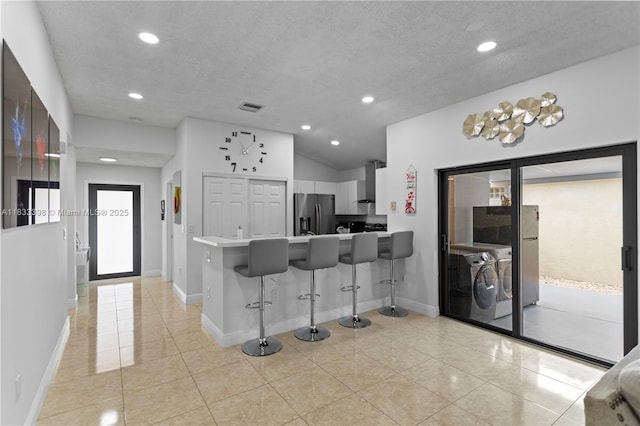 5400 NW 184th St, Miami Gardens, FL 33055 - kitchen with stainless steel refrigerator with ice dispenser, washer and clothes dryer, wall chimney range hood, a breakfast bar, and a peninsula