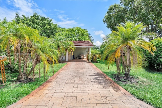 220 NW 35th Ct, Oakland Park, FL 33309 - obstructed view of property featuring driveway, a tile roof, stucco siding, a carport, and a front yard