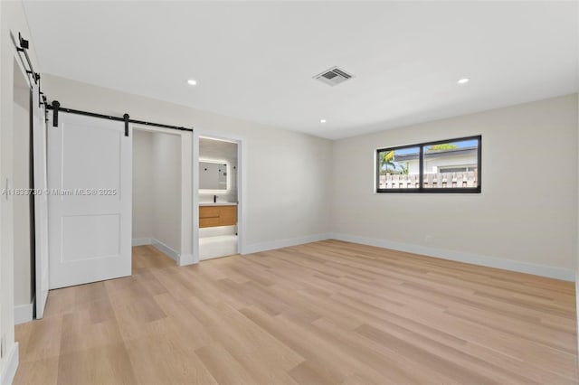 1340 SW 27th Pl, Boynton Beach, FL 33426 - unfurnished bedroom with a barn door, light wood-type flooring, recessed lighting, and ensuite bath