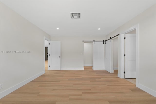 1340 SW 27th Pl, Boynton Beach, FL 33426 - unfurnished bedroom with a barn door, recessed lighting, and light wood-style flooring