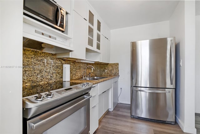 2400 NE 9th St Unit 201, Fort Lauderdale, FL 33304 - kitchen with stainless steel appliances, white cabinetry, backsplash, and glass insert cabinets