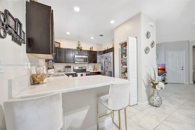 3777 SE 1st St, Homestead, FL 33033 - kitchen featuring stainless steel appliances, dark brown cabinetry, light countertops, a peninsula, and light tile patterned floors