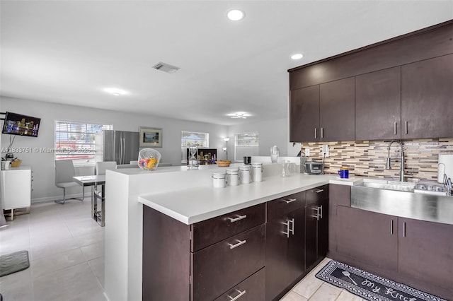 20000 SW 114th Ave, Miami, FL 33189 - kitchen featuring light countertops, a peninsula, backsplash, light tile patterned floors, and dark brown cabinets