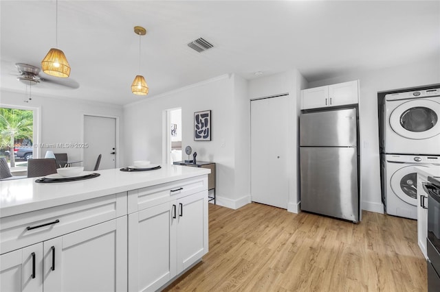 2050 NW 30th Ave, Fort Lauderdale, FL 33311 - kitchen featuring freestanding refrigerator, stacked washing machine and dryer, light countertops, decorative light fixtures, and white cabinetry