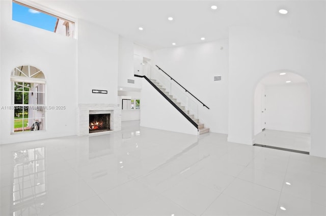 8250 SW 187th St, Cutler Bay, FL 33157 - unfurnished living room featuring a high ceiling, tile patterned flooring, arched walkways, a lit fireplace, and healthy amount of natural light